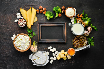 Group of products rich in calcium. Healthy diet food: cheese, milk, parmesan, sour cream, fish, almonds, parsley, garlic, broccoli. On the old background. Top view. Free copy space.