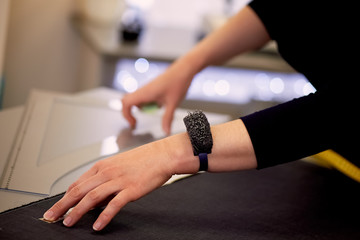 Obraz premium The seamstress lays out the fabric for cutting using inches. Hands in shot.