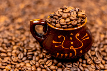 Coffee beans in brown ceramic cup on wooden black table. Side view, soft selective focus, copy space.