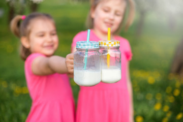 Bottles with milk in children's hands. Childhood, happiness, summer