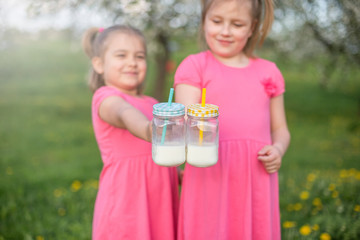 Fototapeta premium Bottles with milk in children's hands. Childhood, happiness, summer