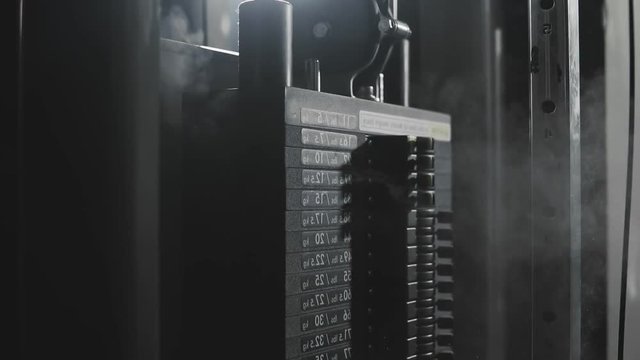 Weight falling in block machine and cloud of powder raising in dark gym in slo-mo.