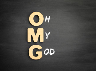 Wooden alphabets building the word OMG - Oh My God acronym on blackboard