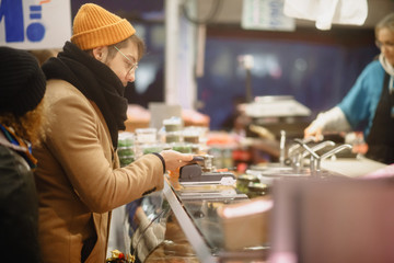 Contactless payment. A man pays with a phone on the market. Checkout Counter Customer Pays with Smartphone for His Items. Modern Wireless Paying Terminal System