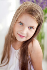 Fototapeta premium Portrait of pretty little emotion girl among violet flowers.Clouse up picture of beautiful smiling girl