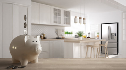 Wooden table top or shelf with white piggy bank with coins, scandinavian white and wooden kitchen, expensive home interior design, renovation restructuring concept architecture
