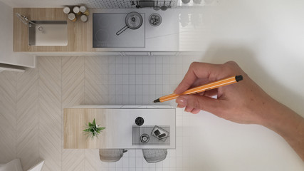 Top view, architect interior designer concept: hand drawing a design interior project and writing notes while the space becomes real, white and wooden modern kitchen plan, above