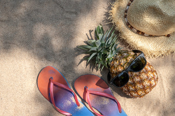 straw hat , pineapple fruit with sunglasses  and flip flop sandals  on the beach sand , summer...