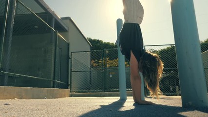 Active 8 year old school girl exercising upside down in school yard outdoors. Slow motion, 4K UHD. 