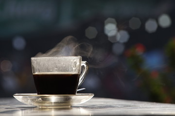 Beautiful steam over a coffee cup with bokeh background in a morning