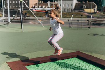 Cheerful adorable girl jumping outdoors in kindergarten.Happiness, sport, leisure, childhood, healthy concept