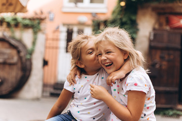 Cheerful happy girl travel together, hugging, holding hands and laughing outdoors in old town....