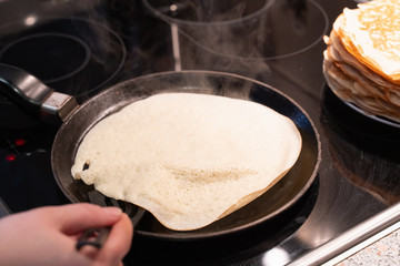 pancakes fry in a pan. the process of cooking pancakes on an electric stove