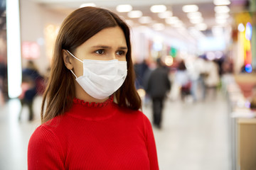 an alarmed young girl frowns and looks away. she is in the Mall and is afraid of infection. the...