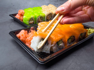 tasty sushi bar, Eating Sushi with chopsticks. California Sushi roll set with salmon, vegetables, fish, caviar closeup. Japan restaurant menu