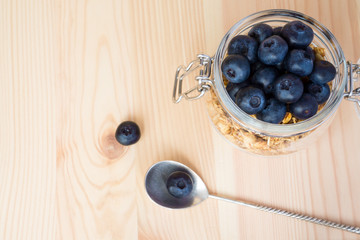 Oatmeal granola with blueberries in a glass jar on a wooden background with copy space