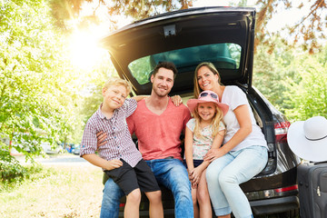 Familie mit Kindern am Auto im Sommer