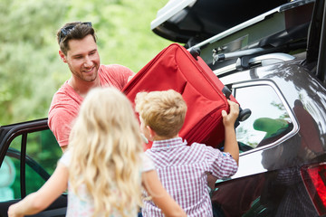 Kinder helfen Vater beim Koffer Verstauen