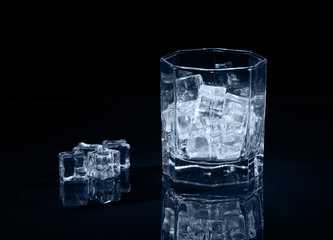 Ice cubes in empty glass on dark background.