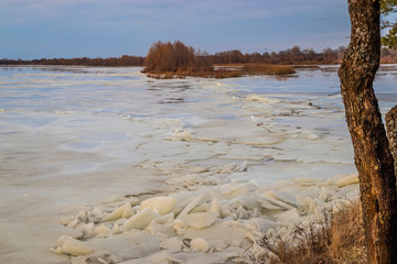 The descent of ice in the spring on the river in March is a natural phenomenon against the sky and clouds in the evening.