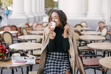Young beautiful woman drinking coffee in a street cafe