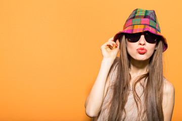  Happy young beautiful woman wearing sunglasses and hat over bright orange background