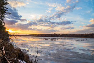 The descent of ice in the spring on the river in March is a natural phenomenon against the sky and clouds in the evening.