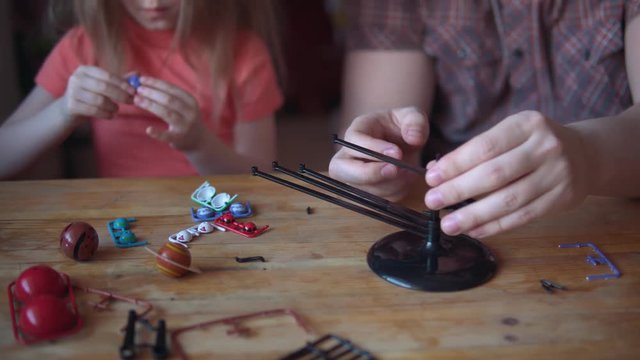 Little cute girl and young man model the layout of the solar system. Father helps his daughter to create a scientific project. Close-up hands collect mockup.