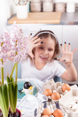 Obraz na płótnie Canvas Little girl paints eggs for Easter in the kitchen at home. Child and holiday items of spring. A happy child draws. Copy space.
