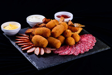 cheese balls and salami sliced on a dark background