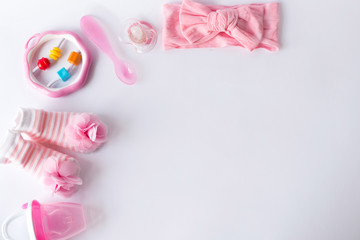 Baby girl accessories and toys on white background with blank space for text; top view, flat lay