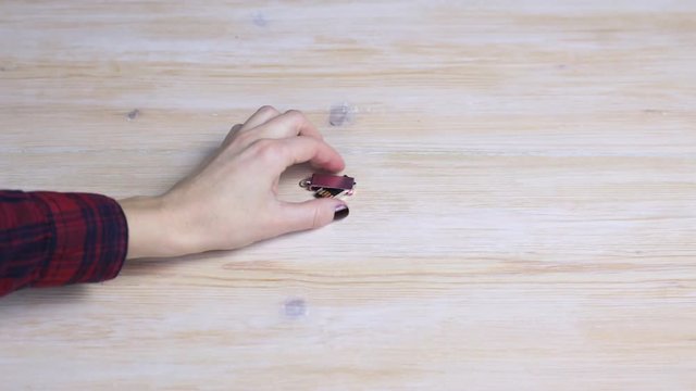 Female hand picks up a small pink USB flash drive from a wooden table