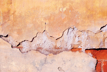 Cracked yellow paint, plaster surface on wall, grunge horizontal shabby background detail close up