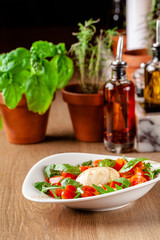 Concept of Italian cuisine. Caprese salad with cherry tomatoes, arugula and basil salad mix, and mozzarella cheese. Serving dishes in white plate in a restaurant. background image.