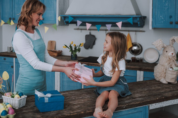 Happy mom giving pink present box to her daughter