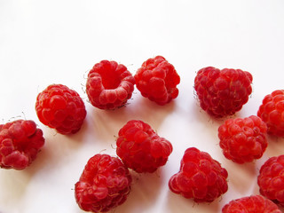 Red raspberry berries scattered, isolated on white background, close-up. Ripe juicy organic Rubus idaeus, beautiful fruit background with copy space