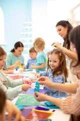 Group of preschool children drawing with pencils and gluing with glue stick on art class in kindergarten or daycare centre
