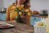 Young woman with yellow tulips on kitchen