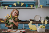Charming girl holding yellow tulips on kitchen