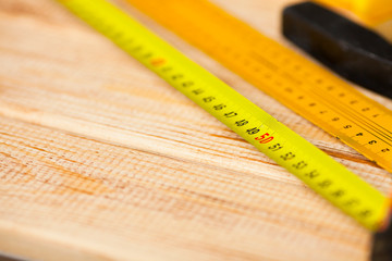 Yellow tape measure tool on the wooden background. close up. Space for a text.