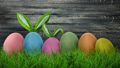 Sweet Easter background with colored eggs in grass on dark background