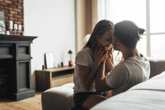 Young romantic couple is kissing and enjoying the company of each other at home