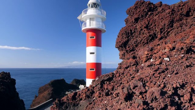 Pedestal view of a lighthouse located in a volcanic cliff in Punta de Teno, Tenerife (Canary Islands), in the background the isle of La Gomera. HD cropped edit