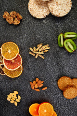 Obraz na płótnie Canvas Healthy snacks - variety oat granola bar, rice crips, almond, kiwi, dried orange