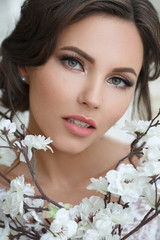 Beauty portrait of a beautiful girl with an elegant wedding makeup with blossoming sakura.