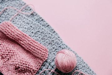 Grey and violet  knitted fabric with yarn skein on a pink background