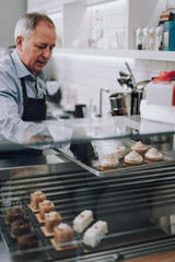 Senior man preparing delicious pastries for sale