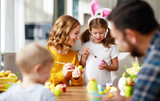 Happy easter! family mother, father and children paint eggs for holiday.