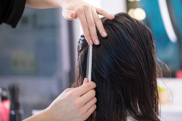 Fototapeta premium Close up of barber making hairstyle for client using hairbrush in saloon