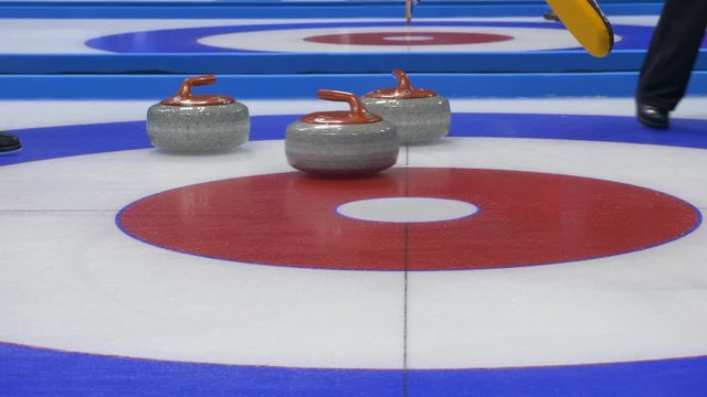 Curling player throw and delivering a stone on a curling rink, sliding over ice